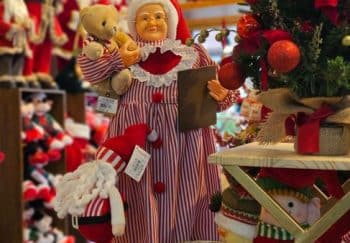 Vibrant Christmas store display featuring Mrs. Claus with teddy bear, surrounded by festive decor.