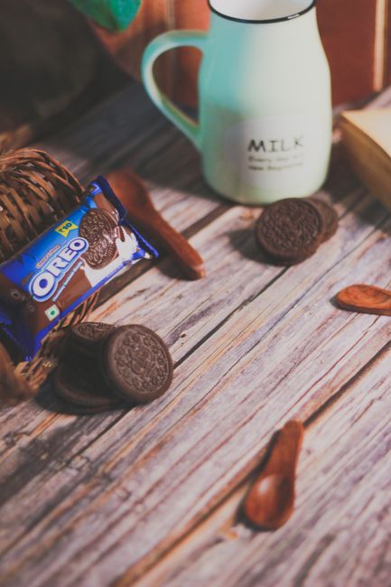 A rustic flat lay of Oreos with milk on a wooden surface, ideal for snack themes.