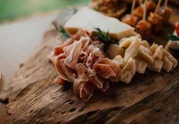 Close-up view of a gourmet cheese and prosciutto platter on rustic wooden board.