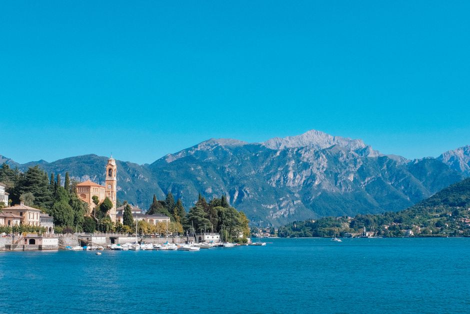 Idyllic Lake Como view with mountains and charming architecture under a clear blue sky.
