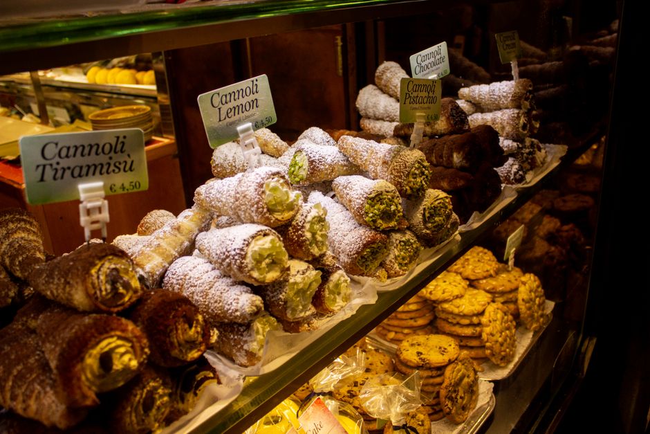 Mouthwatering assortment of Italian cannoli and pastries on display in a bakery. Perfect for food lovers.