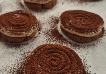 Close-up of homemade tiramisu cookies dusted with cocoa powder arranged on a white background.