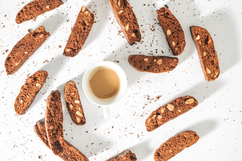 Overhead shot of chocolate biscotti and coffee cup on white surface, creating a rustic setting.