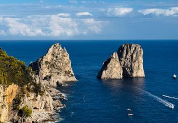 Breathtaking view of iconic Faraglioni rocks on a sunny day in Capri, Italy.