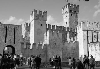 Historic castle with tourists in black and white, showcasing medieval architecture.