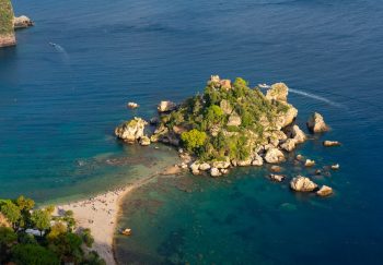 A breathtaking aerial shot of Isola Bella in Sicily, Italy, showcasing its vibrant greenery and crystal-clear blue waters.