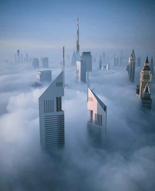 Stunning aerial view of Dubai skyscrapers enveloped in fog, featuring Burj Khalifa.