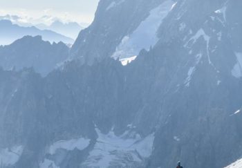 Hikers ascent snow-covered slopes of Chamonix, France with majestic mountains in the background.