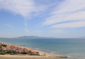 A scenic coastal village with orange rooftops by the tranquil azure sea under a bright sky.