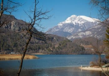 Breathtaking winter landscape of Lago di Cavazzo with snowy mountains in Friuli-Venezia Giulia, Italy.