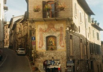 A picturesque street view in Assisi, showcasing historic architecture and vibrant ambiance.
