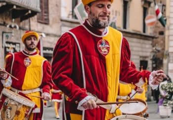 Drummers in traditional Renaissance costumes perform in a European street festival.