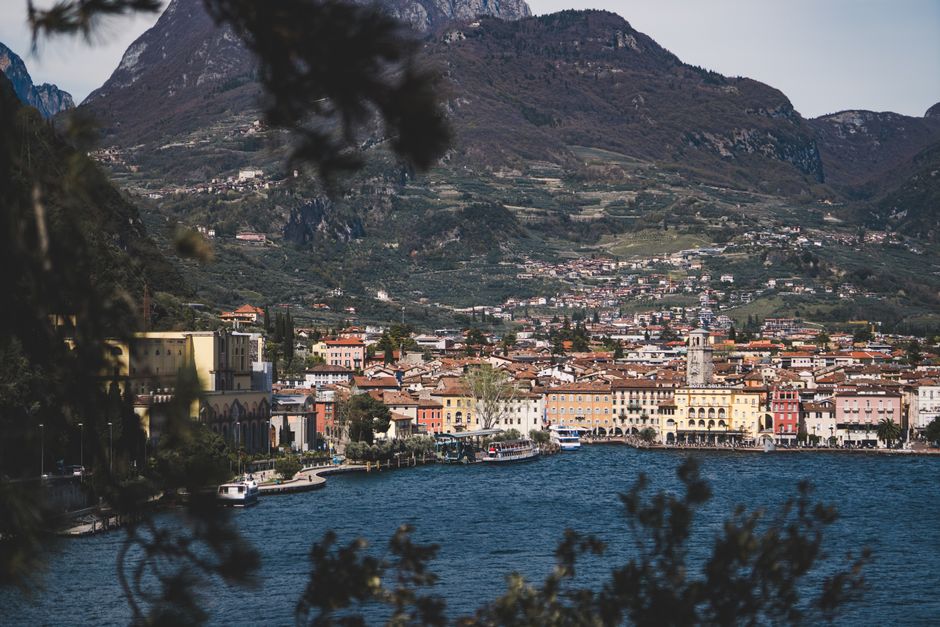 Picturesque view of Riva del Garda against mountainous backdrop with Lake Garda in the foreground.