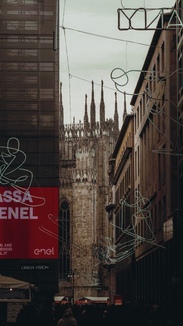 Dramatic urban scene with Milan Cathedral in the background, captured from a busy street with neon art installations.