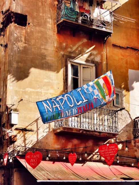 Colorful banner and rustic balcony in Naples, Italy's historic neighborhood.