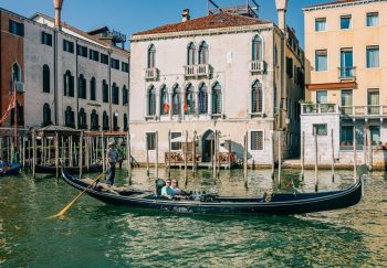 Tourists enjoy a gondola ride on a sunny day in Venice, Italy.
