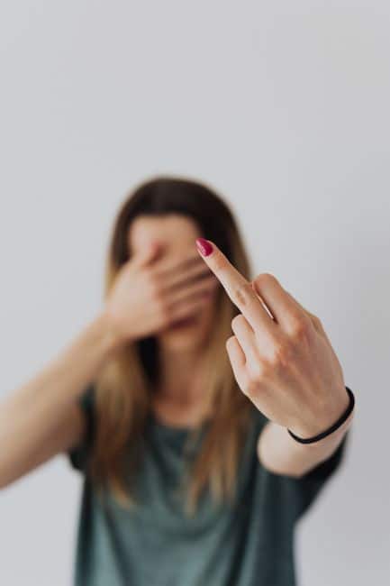 A woman indoors showing a bold gesture with her middle finger extended. Focus on hand.