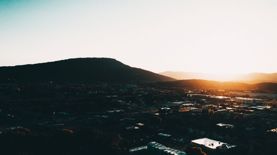 Picturesque scenery of small city located in mountainous terrain against cloudless sunset sky