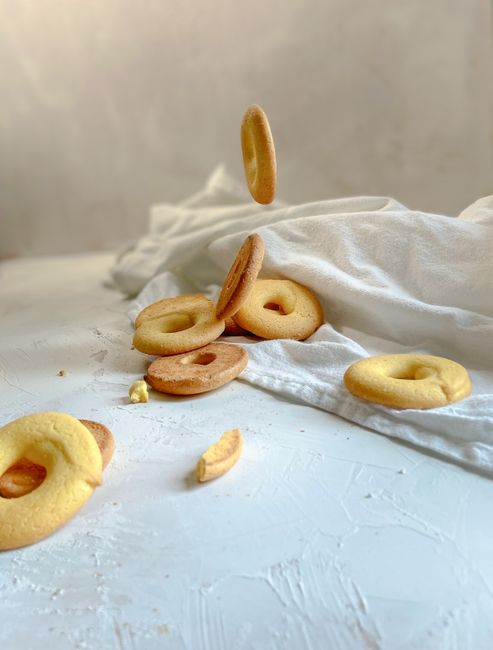 A close-up shot of Italian biscotti falling on a textured white surface, creating a dynamic food scene.