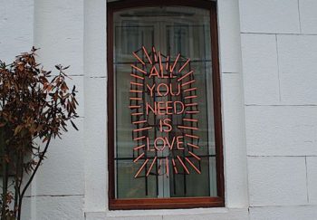 A vibrant neon message displayed in a window highlights love in urban architecture.