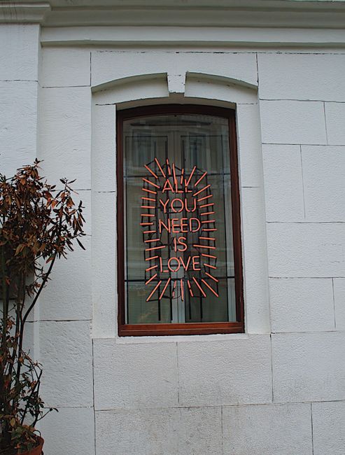 A vibrant neon message displayed in a window highlights love in urban architecture.