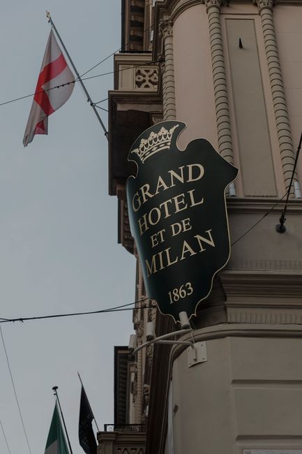 Street view of the iconic Grand Hotel et de Milan's facade with flags displayed prominently.