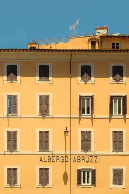 Charming view of Albergo Abruzzi hotel facade in Rome, Italy, under clear blue skies.