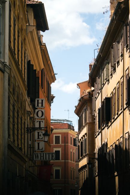 A picturesque street with classic architecture and a hotel sign in Rome.