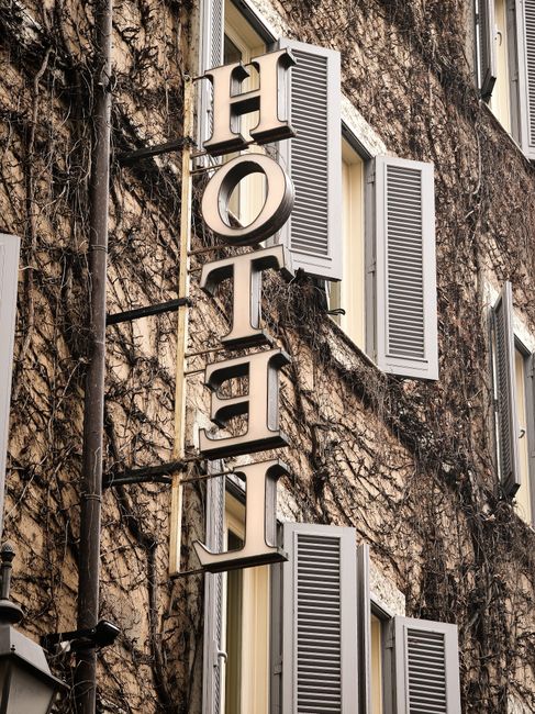 Warm-toned hotel facade covered in ivy vines with classic architectural details in Rome, Italy.