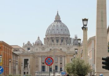 Tourists gather near St. Peter's Basilica in Rome on a sunny day.