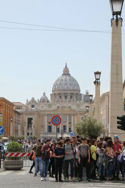 Tourists gather near St. Peter's Basilica in Rome on a sunny day.
