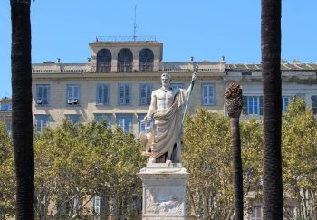 A stunning statue of Napoleon Bonaparte in Bastia, Corsica, set against historical architecture.