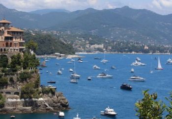 A stunning view of boats in Portofino Bay, Italy, set against lush greenery and mountains.