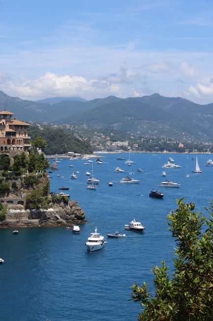 A stunning view of boats in Portofino Bay, Italy, set against lush greenery and mountains.