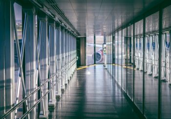 Sunlit airport jet bridge with reflections and aircraft visible outside, RS, Brazil airport.