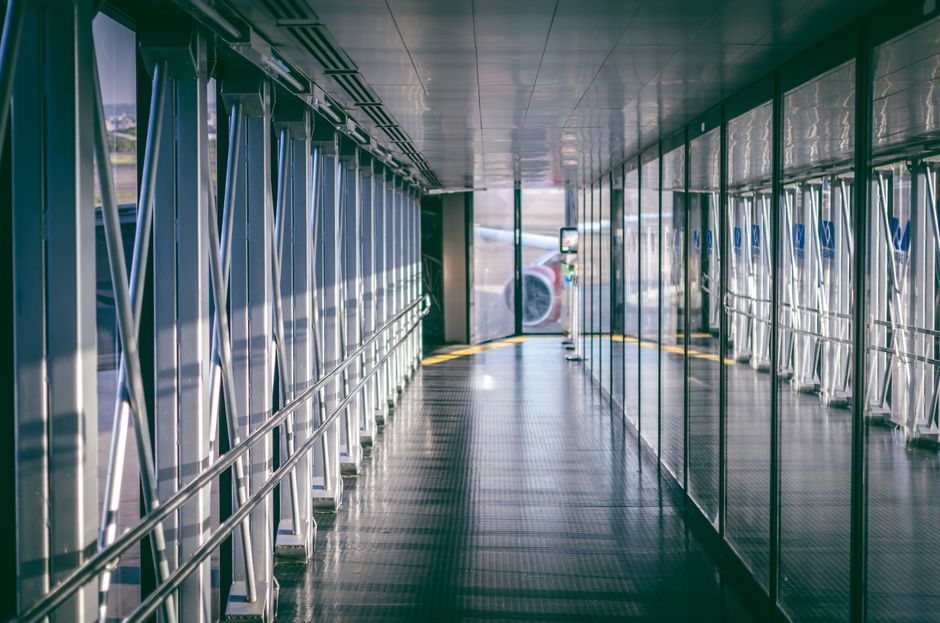 Sunlit airport jet bridge with reflections and aircraft visible outside, RS, Brazil airport.