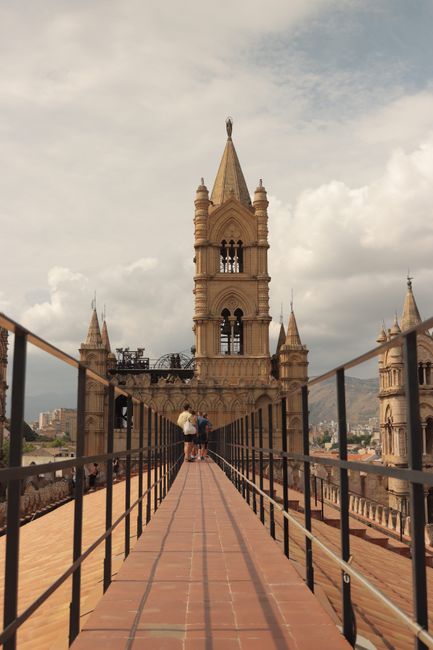 Tourists walking along the rooftop path of Palermo Cathedral with a view of its iconic bell towers.