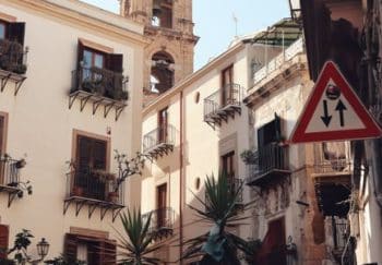 Charming street in Palermo, Sicily showcasing historical architecture and vibrant urban life.