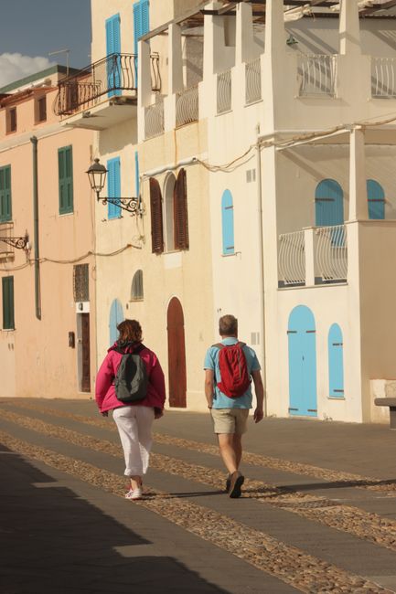 A couple enjoying a leisurely walk along Alghero's charming streets in Sardinia, Italy.
