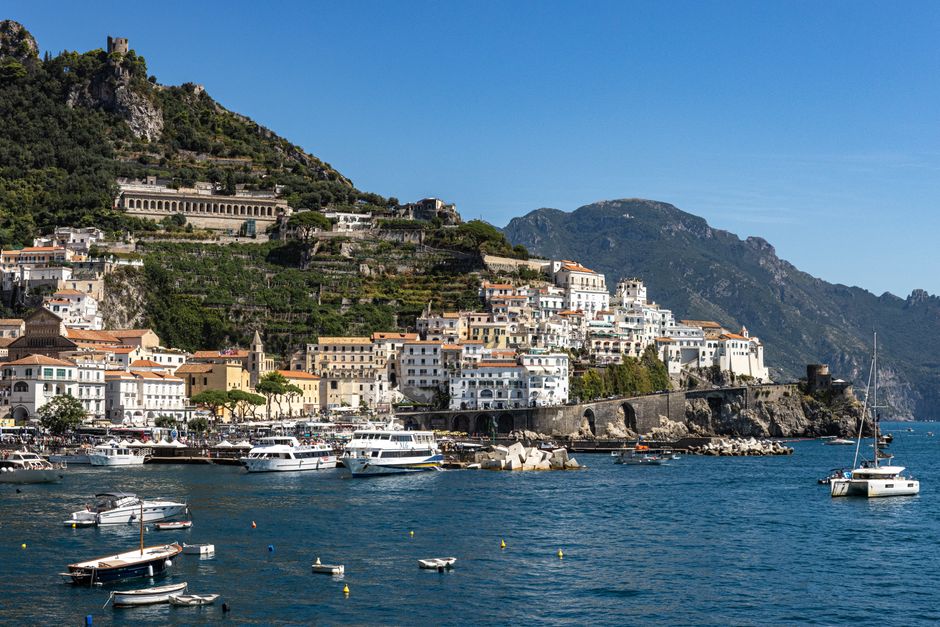 Breathtaking view of Amalfi's coastal town and marina under a clear summer sky in Italy.