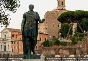 A historic statue of a Roman figure in a scenic Roman square, showcasing ancient architecture.