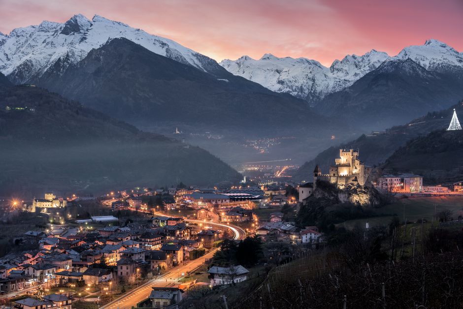Enchanting evening view of Saint-Pierre with snow-capped mountains and a lit castle.