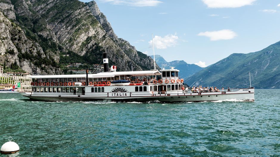 Historic steamboat cruising on Lake Garda with mountains in the background.