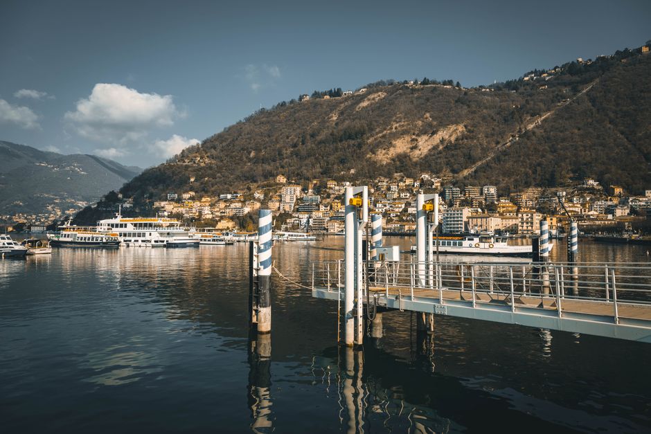 Beautiful view of Lake Como featuring harbored boats and scenic mountains in Italy.