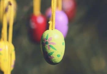 Decorative Easter eggs hanging on strings in a garden, capturing a festive, vintage feel.