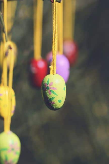 Decorative Easter eggs hanging on strings in a garden, capturing a festive, vintage feel.