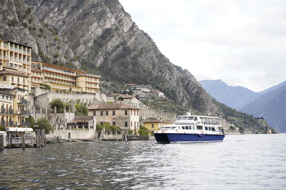 Stunning view of Limone Sul Garda with mountains, buildings, and a boat on the lake.