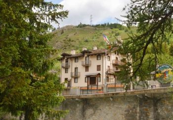 Picturesque mountain house in Valle d'Aosta, Italy by a vibrant river in summer.