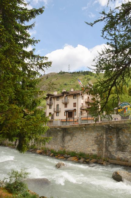Picturesque mountain house in Valle d'Aosta, Italy by a vibrant river in summer.
