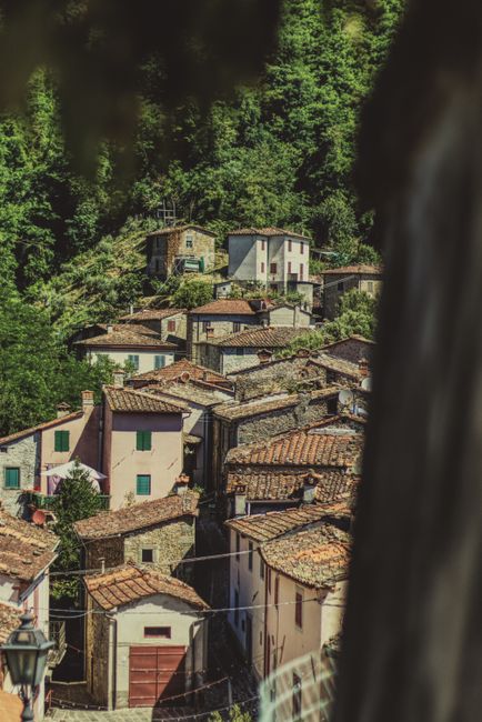 A picturesque view of a rustic village in Lucca, Tuscany, featuring traditional stone houses with terracotta roofs.